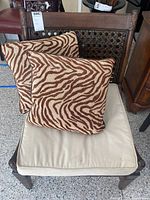 Wooden chair with woven backrest, beige seat cushion and two animal print pillows on seat