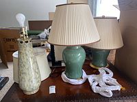 View of two ceramic lamps with shades and one modern white lamp without shade on wooden table, showing the fully assembled set