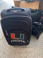 Two black soft-sided suitcases with University of Miami logo.