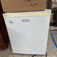 Front view of white Emerson mini refrigerator with a label sticker and power cord visible.