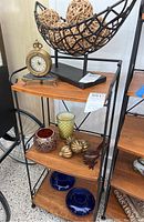 Shelf with table decor including desk clock, candleholders, bird statue, and blue plates
