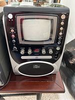 Full front view of The Singing Machine karaoke player showing screen, speaker, and main controls.