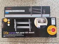 Two boxed TV wall mount systems stacked: Rocketfish 32-70 TV Wall Mount and Omnimount Large/X-Large Flat Panel Tilt Mount.