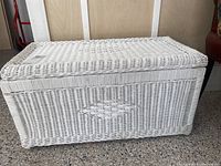 White wicker trunk closed, showing top and side weaving pattern.