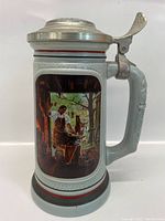 Front view of the Avon mug stein showing the painted image of a blacksmith working inside a workshop with a tree visible outside the window.