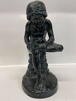 Front view of bronze-colored Boy with Thorn statue, showing seated boy removing thorn from foot.