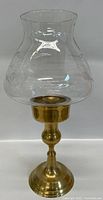 Full view profile of brass hurricane candle holder showing the glass shade and brass base.