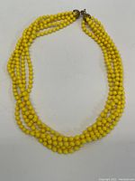 Full view of the multi-strand yellow beaded necklace laid flat, showing the overall design and clasp.