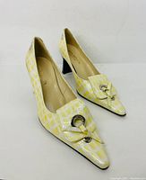 Pair of yellow and white patterned ladies leather shoes with decorative buckle front and distinctive black block heels, photographed front and side angles.