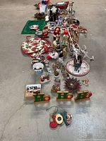Photo showing an array of Christmas decorations arranged on the floor including figurines, signs, ornaments, and string lights