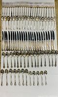 Full lot showing 12 forks, 12 knives, 12 large spoons, and 12 teaspoons arranged neatly on a flat surface.