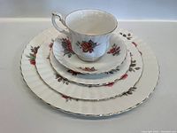 Set of Royal Albert tea cup and three plates showing floral rose pattern and gold trim