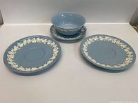 Blue jasperware Wedgwood bowl, saucer, and two plates with white floral relief decoration.