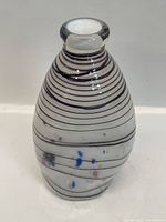 Front and side views of a Murano design glass vase showing black horizontal stripes and colorful spots embedded in clear glass with a rounded body and narrow neck.