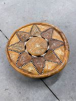 Top view showing sunburst pattern with black and white braided trim on leather panels, central circular padded area with stitched rays.