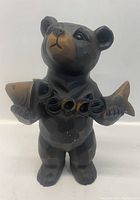 Front view of the carved wooden bear statue holding a fish with 'Peace' carved through it.