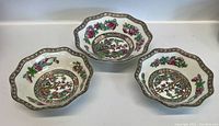Three Coalport bowls arranged showing their scalloped edges, floral design and gold detailing on white ceramic.
