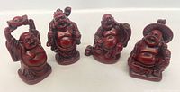 Four red Buddha figurines with different poses and objects, shown together on a white surface.
