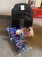 Photo showing black Tracker backpack with three packs of men's size 6-12 low cut athletic socks in various colors, one pack partially opened.