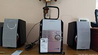 Two Panasonic remote powered speakers with grey cover, black casing, situated on each side of the stereo unit.