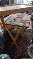 Side view of Simplicity folding tray table standing upright with one rooster-themed placemat on top.