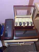 Overhead view of three wooden watch boxes, one loaded with five watches