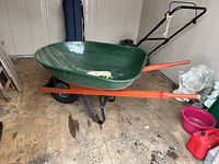 Green Wheelbarrow with black metal frame and brown wooden handles, showing full side profile and tub shape.