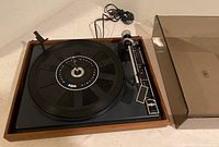 Full view of the BIC turntable on wood trim base with platter and attached tonearm, power cord visible, dust cover removed.