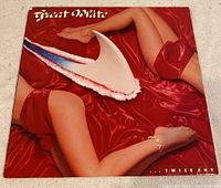 Front cover of Great White Twice Shy vinyl record showing distinctive artwork of woman's legs with a shark tooth necklace on a red satin background.