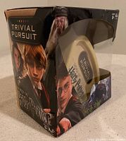 Side view of the Harry Potter Trivial Pursuit game in its box showing the cream-colored triangular case and character images on packaging.