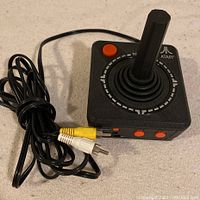 Black Atari joystick plug and play game controller from Jakks 2002 with attached AV cables and buttons visible.