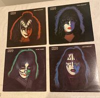 Front covers of four Kiss solo vinyl records featuring individual band member portraits in makeup.