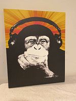 Front view of canvas wall art showing a monkey wearing headphones with an orange and yellow background.