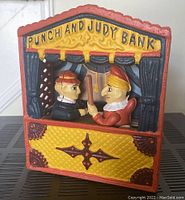 Front view of Punch and Judy cast iron bank showing colorful painted figures and stage design with 'PUNCH AND JUDY BANK' text