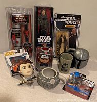 Photo showing multiple Star Wars collectible items including action figures, plush doll, themed drink cups and a Hot Wheels diecast car.