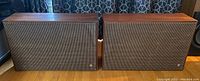 Front view of two Jensen TF-4 slender shelf speakers showing fabric grills and wood casing.