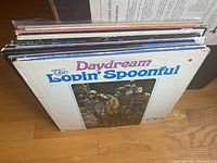 Photo showing several vinyl albums in a vertical stack with The Lovin' Spoonful Daydream album cover visible on front.