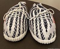 Front view of plush slippers showing black Zebra pattern on white base, laces front.
