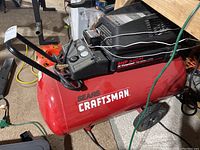 Side view of red tank and motor housing showing Sears Craftsman logo, wheels and handle