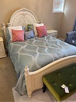 Angled front view of fully made bed showing headboard, footboard, side rails, bedding