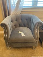 Front view of the grey microfiber armchair showing tufted back, curved arms, and nailhead trim.