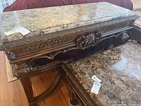 Front three-quarter view showing entire console table with faux marble top and carved base