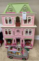 Front view of the Fisher Price three-story doll house with several windows, balcony, and green roof