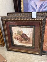 Framed artwork featuring grape still life with ornate carved bronze frame.