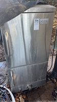 Front view of closed stainless steel smoker with dual doors and tubular handles, branding label visible.