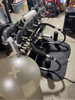 View of the adjustable barbell set with weight plates, black sit-up bar, black exercise mat, and gray exercise ball in basement setting.