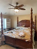 Full view of king size four-poster bed frame assembled in bedroom, showing headboard, footboard, side rails and bedding.