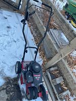 Full view of red Troy-Bilt lawn edger showing metal frame, handles, wheels, and drive engine