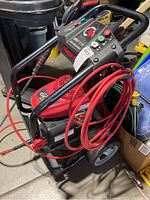 Front view of power washer showing frame, wheels, coiled hose and engine