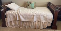 Full view of bed dressed with bedspread, pillows and visible trundle under bed